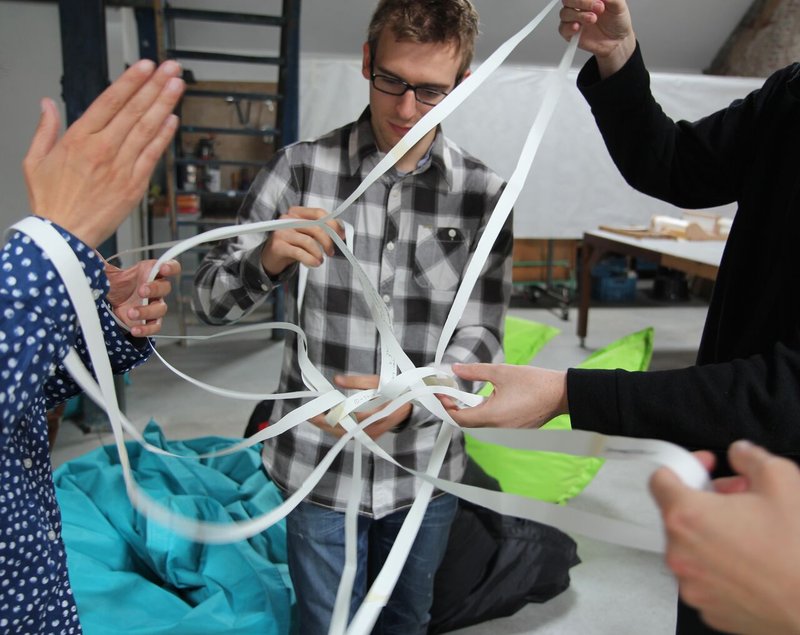 A group of people dissecting and stretching a cut Möbius Strip made out of paper