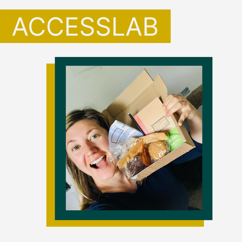 AccessLab image, with a participant grinning holding a small card box containing various biscuits, notebook, pencil, tea etc. which were sent out to all participants.